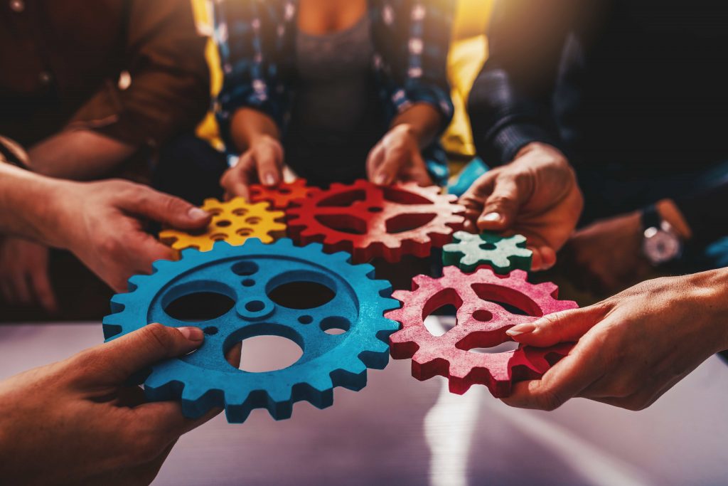 Menschen simulieren mit Zahnrädern ihre Zusammenarbeit