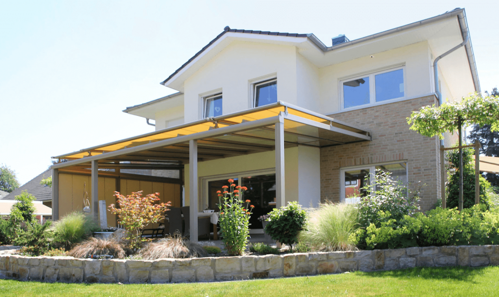 Terrassenüberdachung aus Aluminium an einem Einfamilienhaus mit Garten