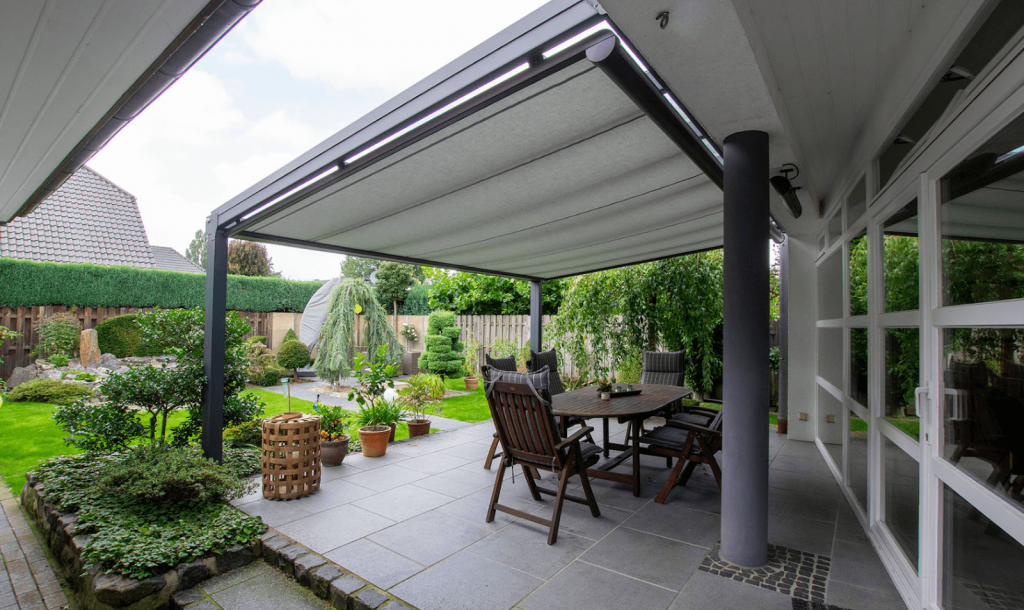 Überdachte Terrasse mit eingefahrener Markise und Sitzbereich im Garten